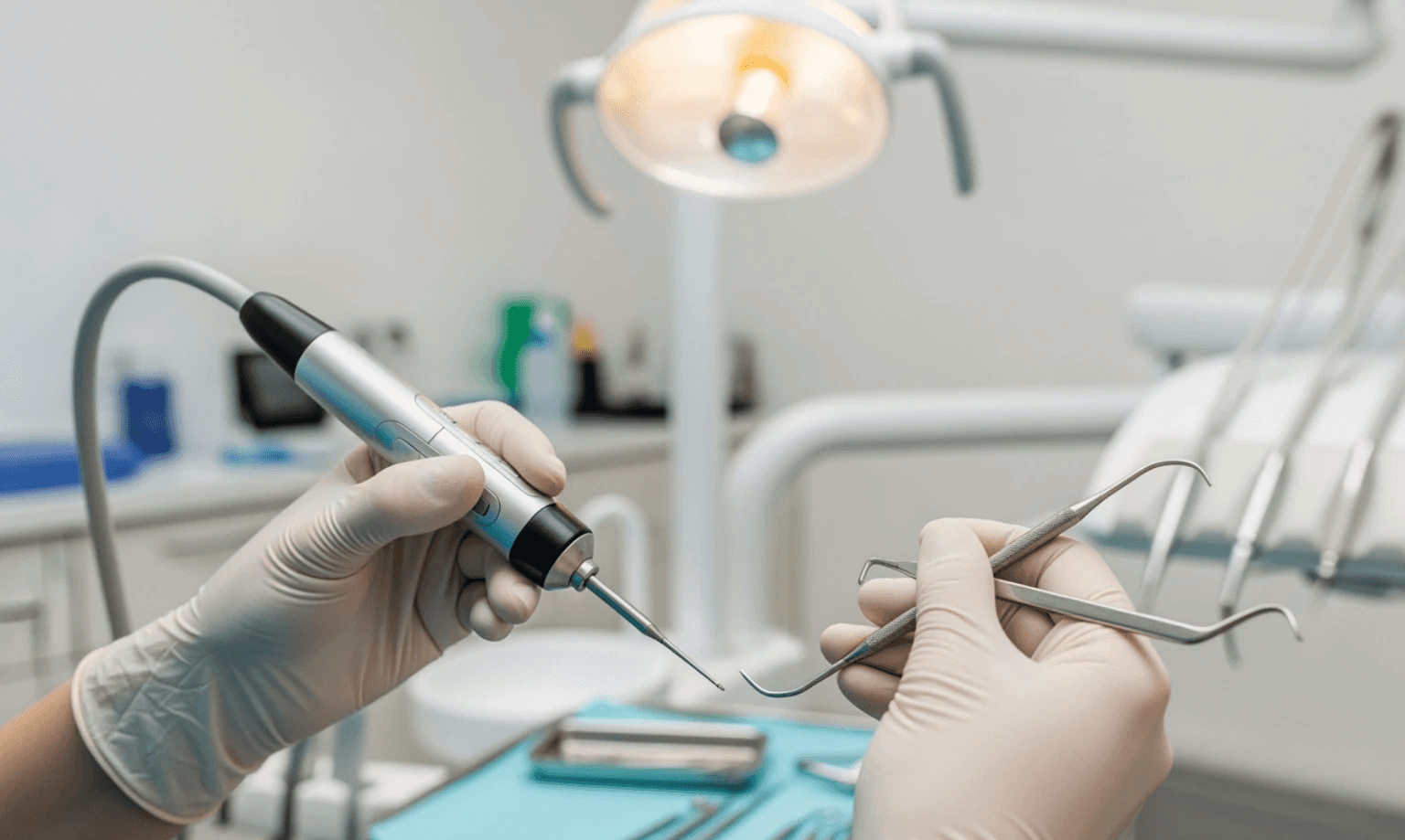 Close-up image of a dental hygienist's hands holding an ultrasonic scaler and a manual scaler, demonstrating the tools used during a deep cleaning procedure - Deep cleaning teeth